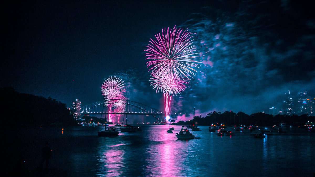 anonymous people in boats floating in river and admiring firework at night